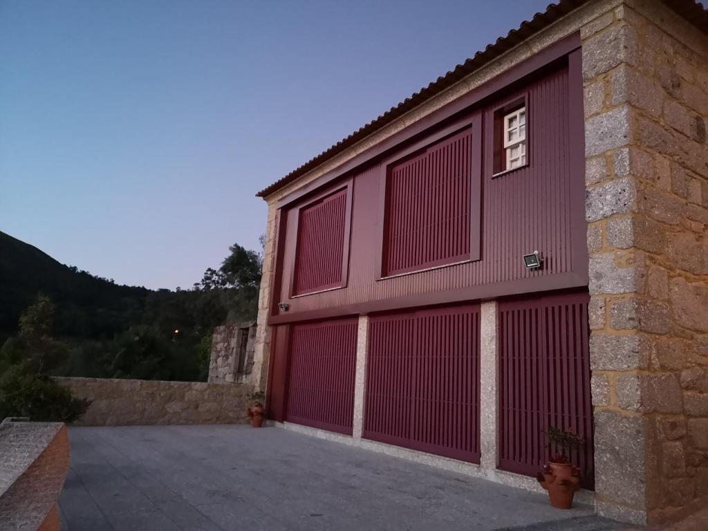 un garage avec deux portes rouges sur un bâtiment dans l'établissement Casa Zé Manel - Turismo Rural, à Paranhos