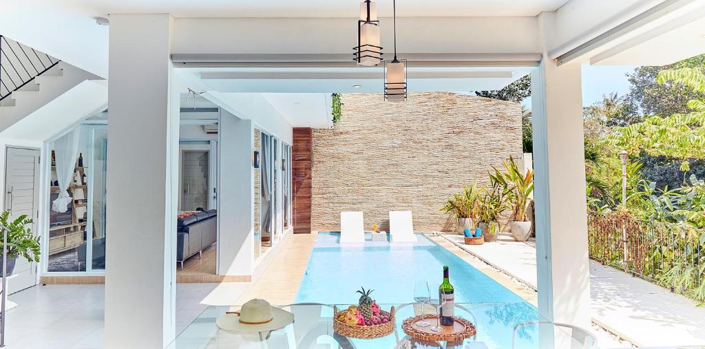 a dining room with a pool and a brick wall at Echo Bali Beach Villas by The Kunci in Canggu