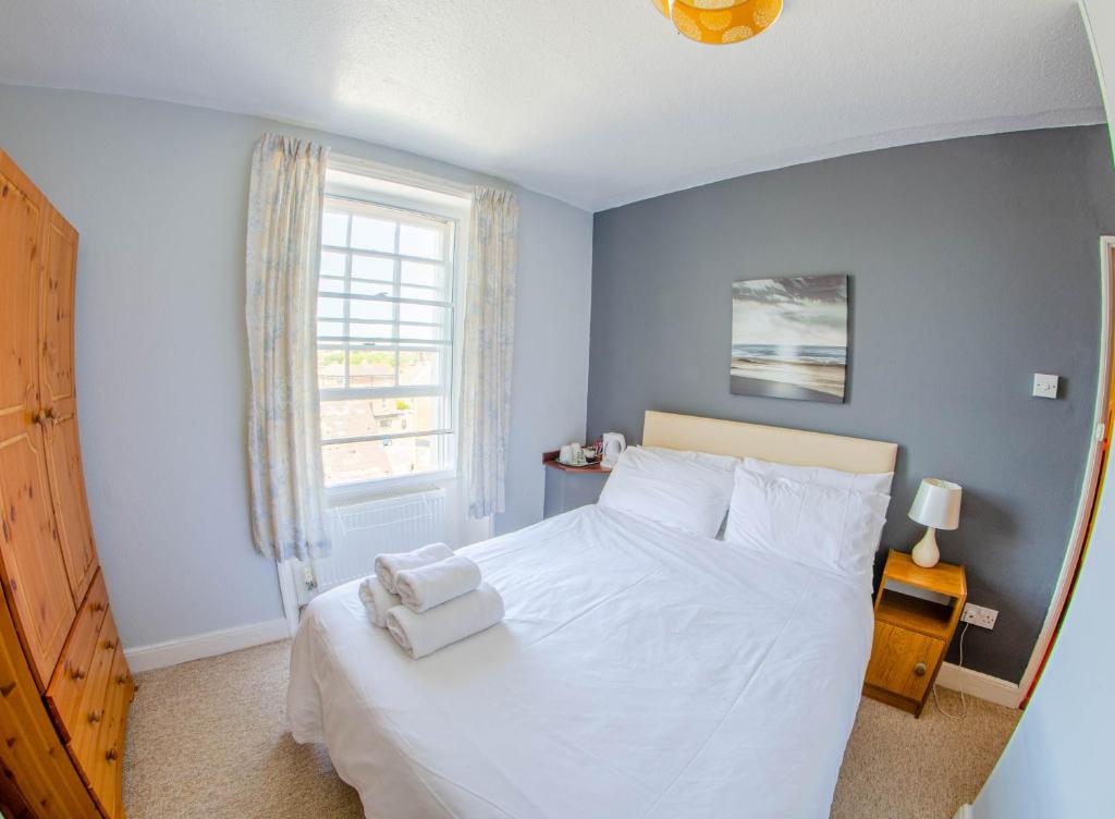 um quarto com uma cama branca e uma janela em Olivers Guest House em Weymouth