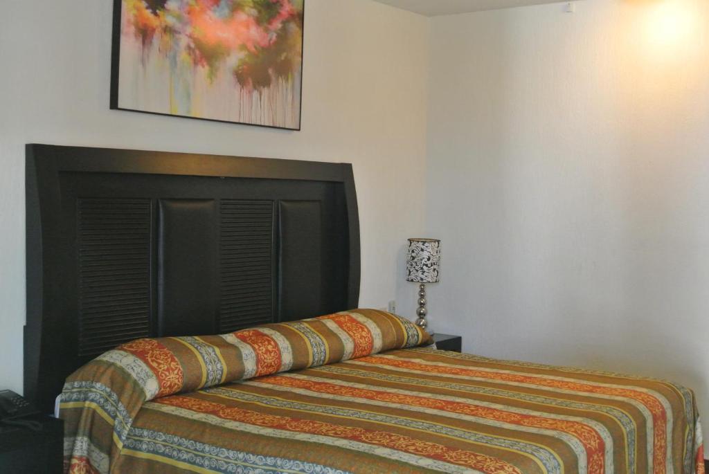 Parque Inn Hotel & Suites في كواتزاكوالكوس: غرفة نوم مع سرير مع بطانية ملونة عليه