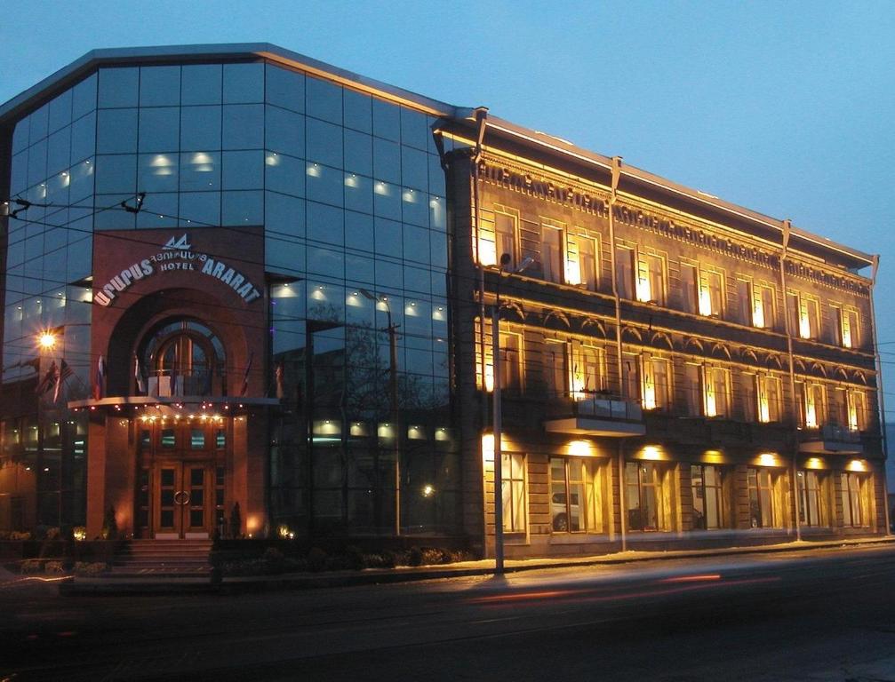 un gran edificio de cristal en una calle de la ciudad por la noche en Ararat Hotel, en Ereván