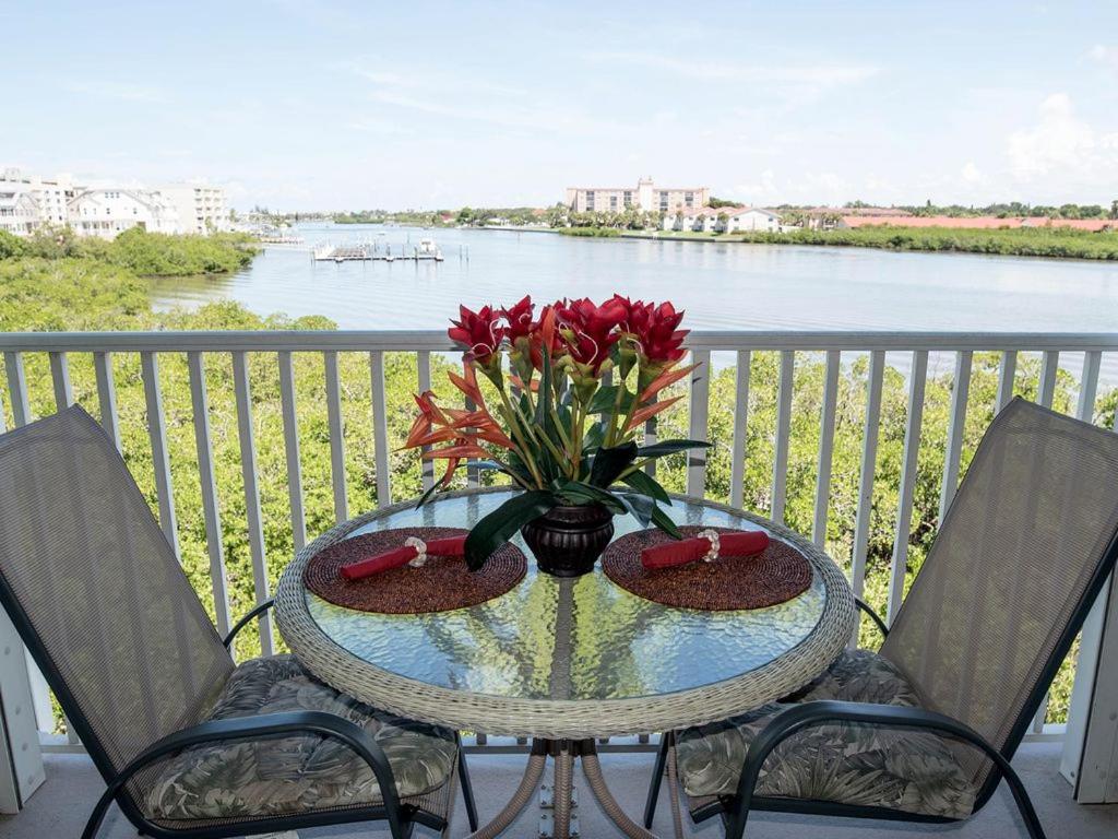 a table with a vase of flowers on a balcony at Gulf Retreat 2: Magnificent Water Views, Steps to Beach, None Cleaner, None Nicer! in Clearwater Beach