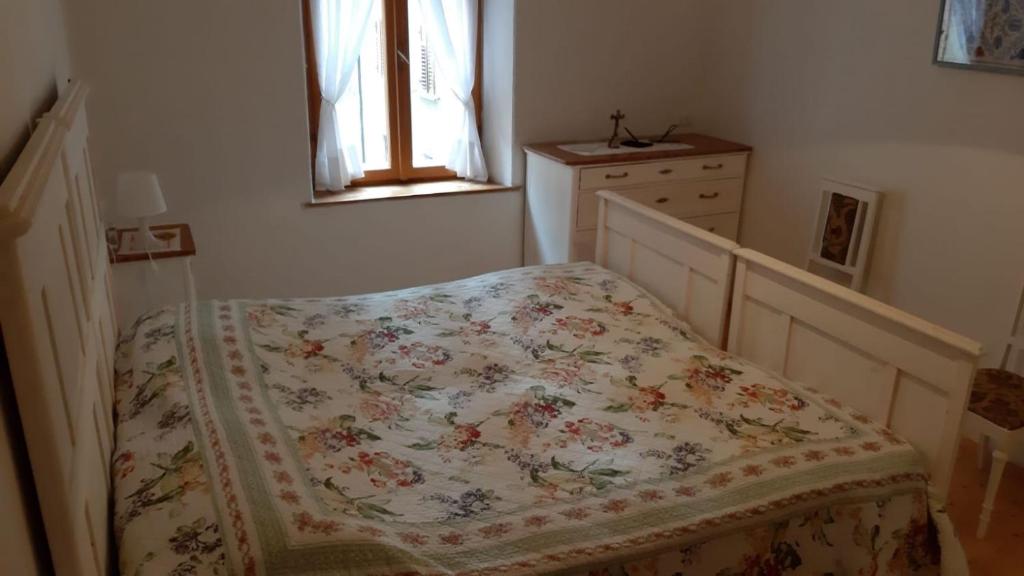 een slaapkamer met een bed met een bloemendeken bij Appartamento Castello Tesino in Castello Tesino