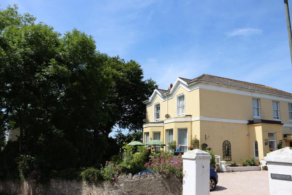 a large yellow house with a fence and trees at Tor View - Sorrento in Torquay