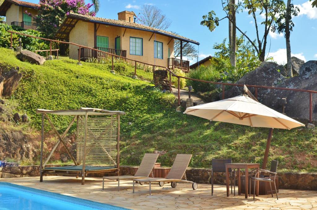 ein Pool mit Stühlen und einem Sonnenschirm und ein Haus in der Unterkunft Cafezal em Flor Turismo e Cafés Especiais in Monte Alegre do Sul