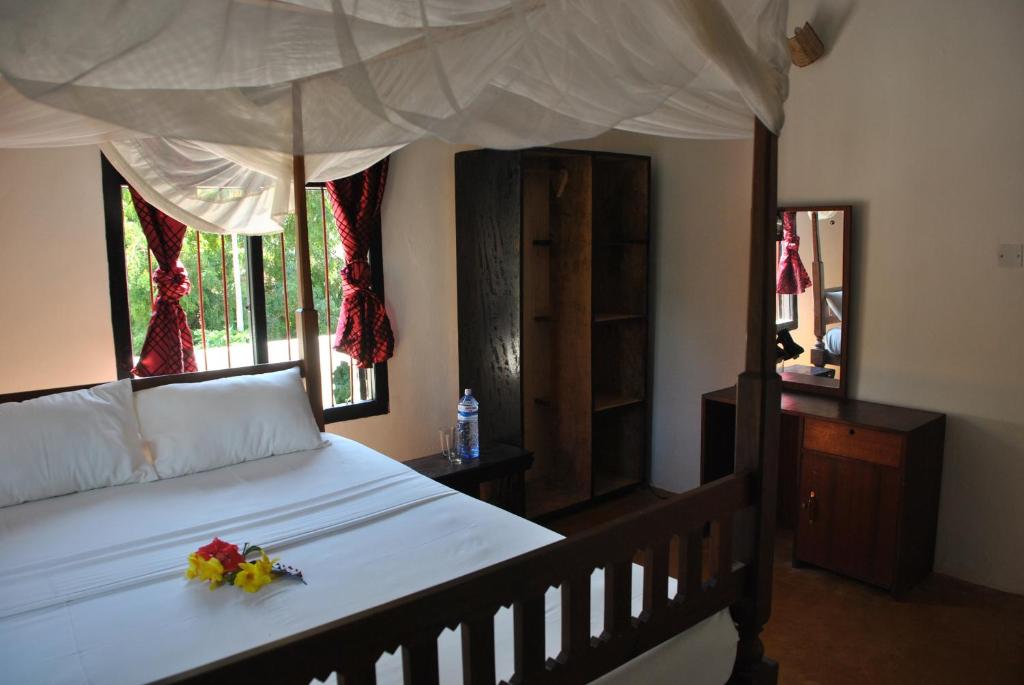 a bedroom with a canopy bed with flowers on it at Shella White House in Lamu