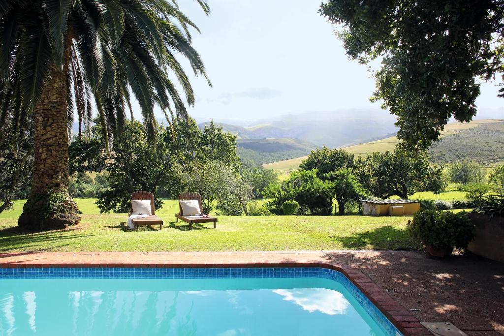 a swimming pool with two chairs and a garden at Joubertsdal Country Estate in Swellendam