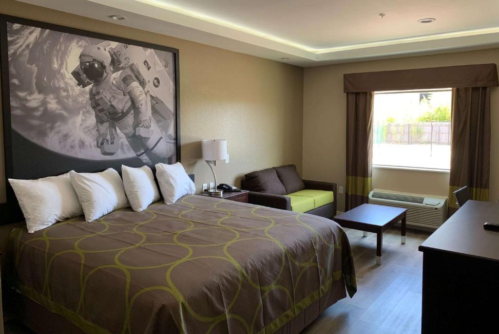 una camera d'albergo con un grande letto e una sedia di Super 8 by Wyndham Kingwood Houston North a Kingwood