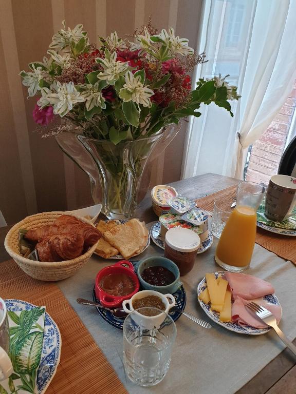 a table topped with a vase of flowers and food at Au Nid de la Madeleine in Gaillac