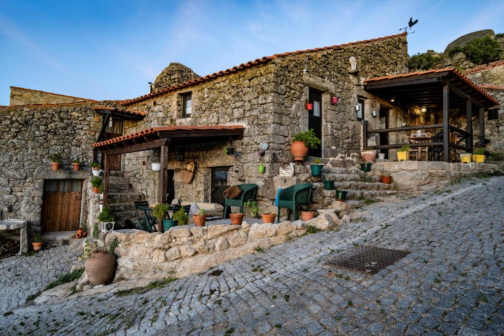 a stone building with plants on a cobblestone street at Old House in Monsanto