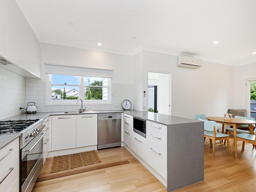 a kitchen with white cabinets and a table with chairs at Marlow House in Port Fairy