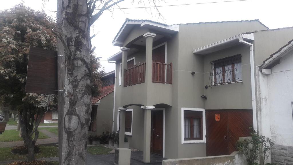a white house with red windows and a tree at Casa de verano con Pileta, Quincho y Garage Parque Luro MDP in Mar del Plata