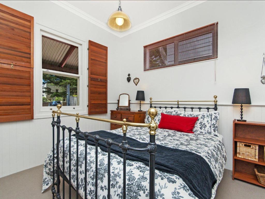 a bedroom with a bed with a red pillow at Railway Cottage in Port Fairy