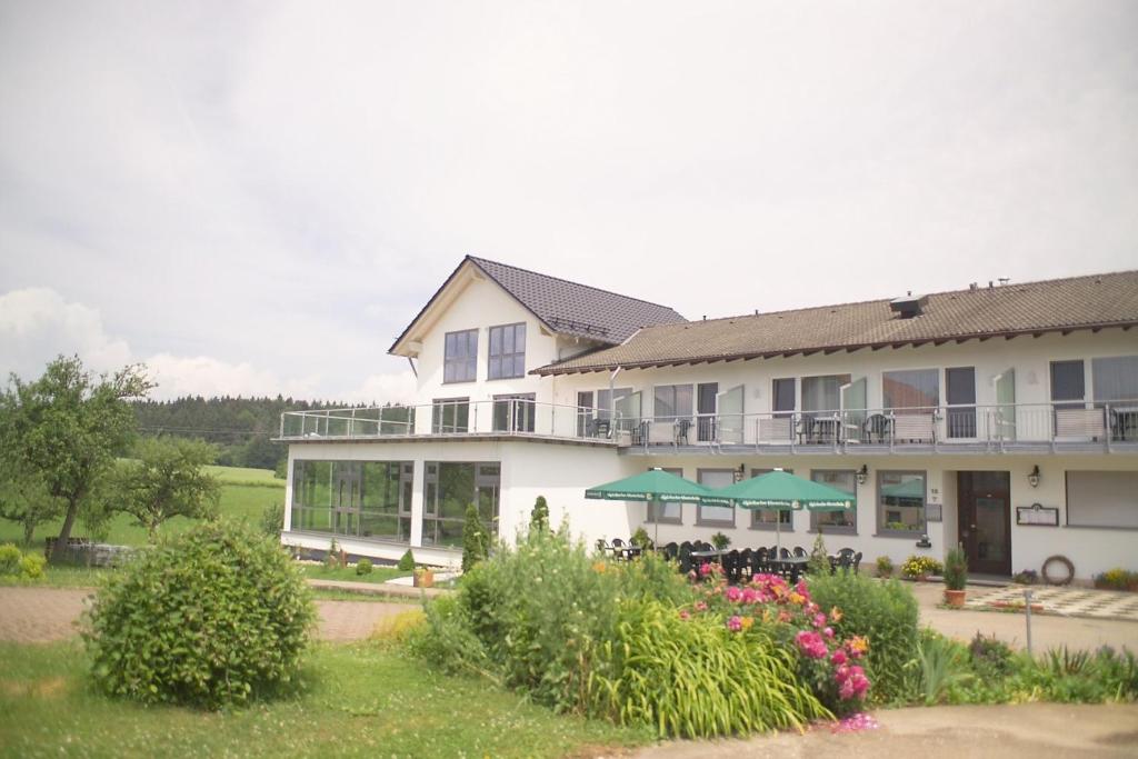 a large white building with tables and chairs and flowers at Hotel-Landgasthof Brachfeld in Sulz am Neckar