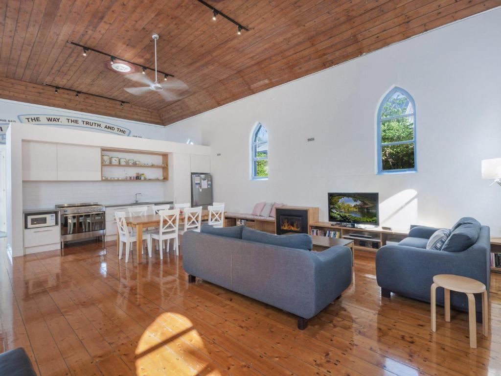 a living room with two blue couches and a kitchen at The Church in Port Fairy