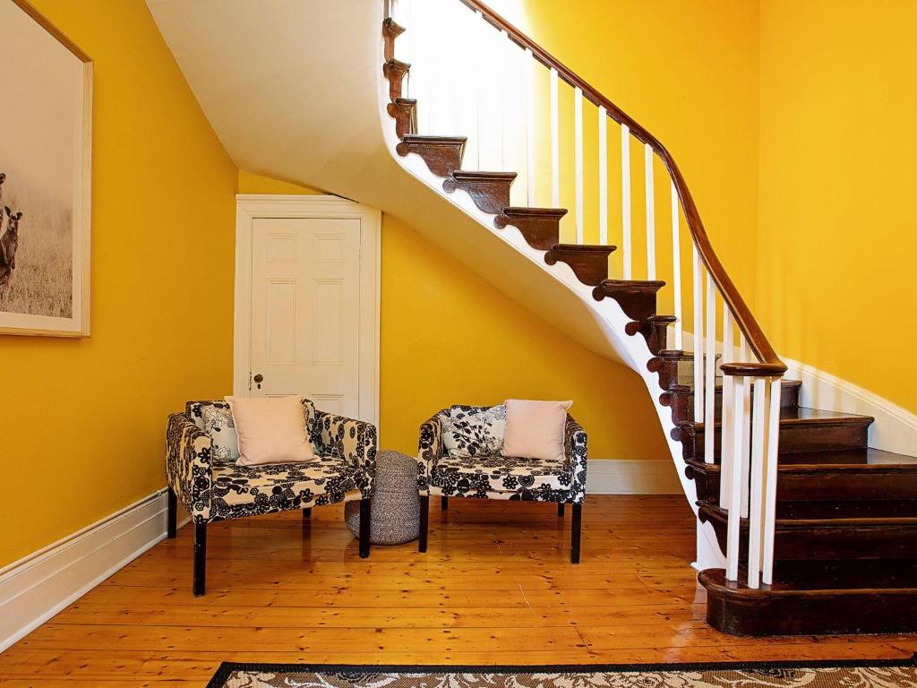 Deux chaises dans un couloir avec des murs et des escaliers jaunes dans l'établissement The Ivy Bank, à Port Fairy