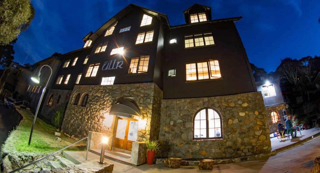 a large stone building with lit windows at night at House of Ullr in Thredbo
