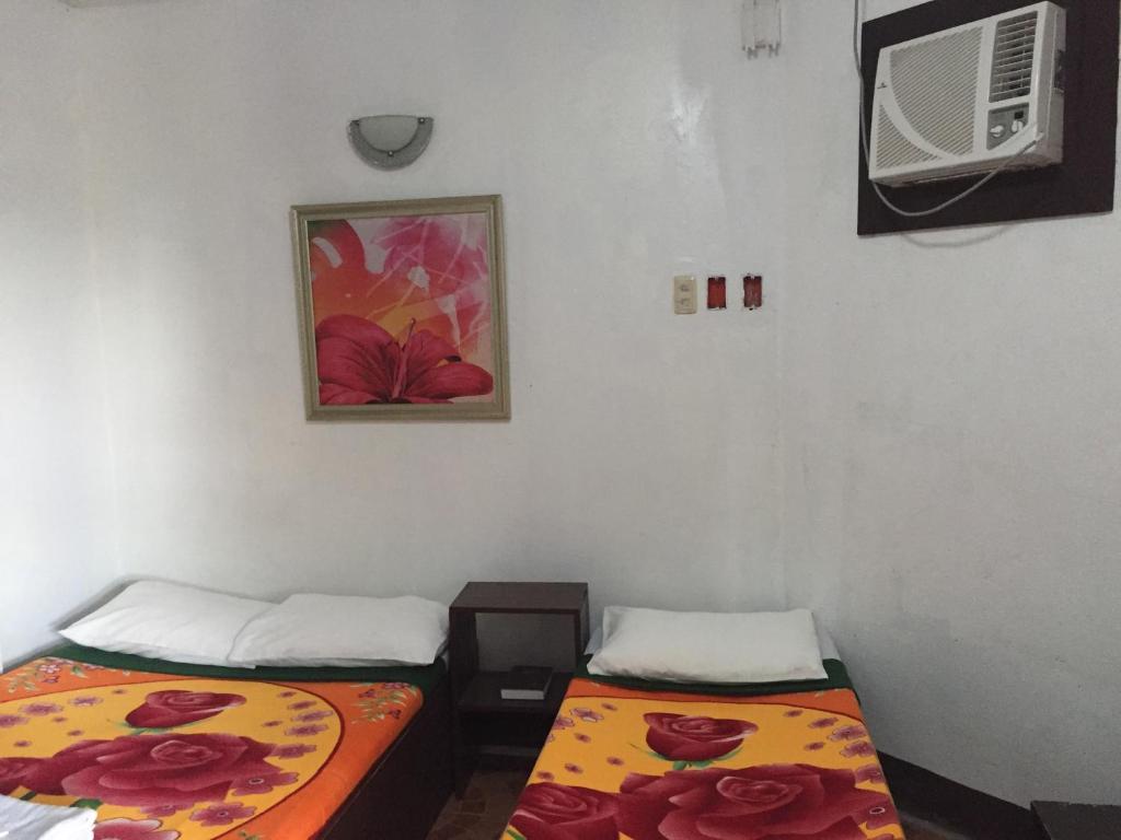 a room with two beds and a air conditioner at Antonio's Pension House in Dipolog