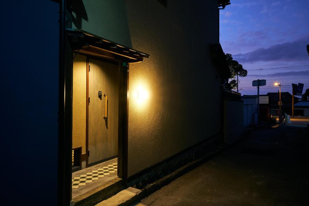 a door to a building with a light on it at Bed and Craft MITU in Nanto
