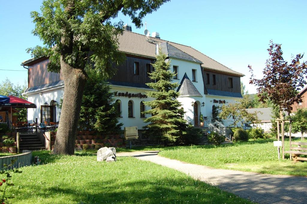 a large white building with a tree in front of it at Landgasthof "Am Park" in Crottendorf