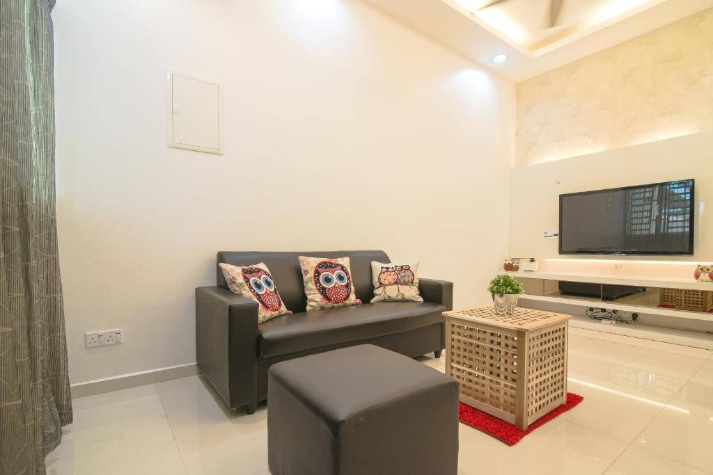 sala de estar con sofá y TV en Landed Cozy House Near SPICE, Airport en Kampong Manggis
