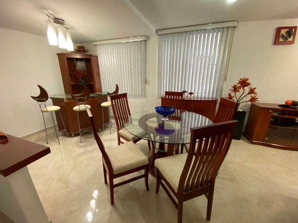 a dining room with a glass table and chairs at Condominio Renoir in Mexico City