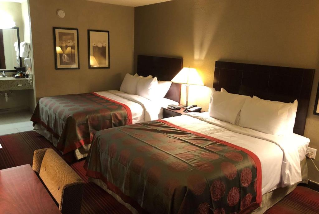 a hotel room with two beds and a lamp at Ramada by Wyndham Michigan City in Michigan City