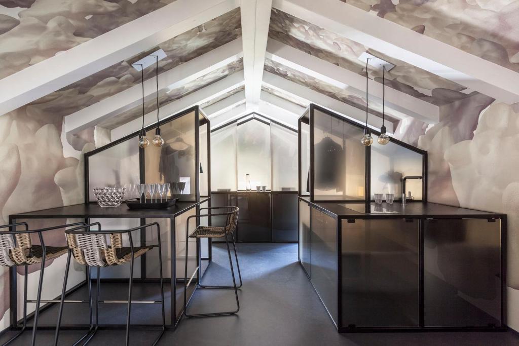 Casa Trentini - Atemporary Art Apartments في ترينتو: غرفة بها طاولات سوداء وكراسي وسقف