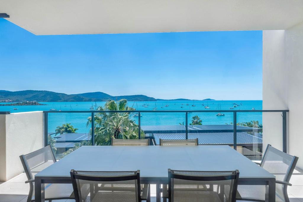 a table and chairs on a balcony with a view of the ocean at Executive on Whisper Bay - Cannonvale in Airlie Beach