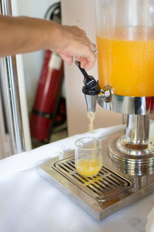 a person pouring an orange juice into a juicer at Riviera Perdika Hotel in Perdika