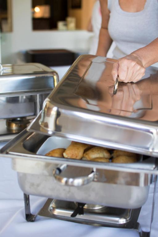 a woman is putting a tray of food in a kitchen at Riviera Perdika Hotel in Perdika