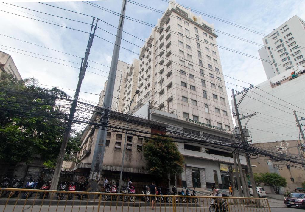 a tall white building with people standing in front of it at RedDoorz at BP International near SM Manila in Manila