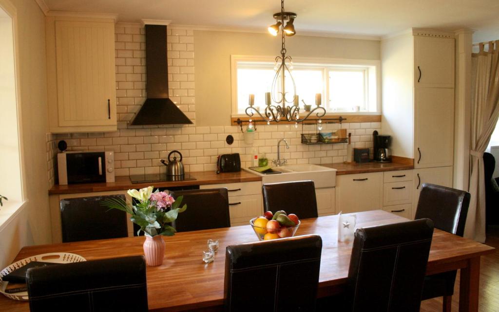 een keuken met een houten tafel met stoelen en een vaas met fruit bij Grönelid Gård in Tived