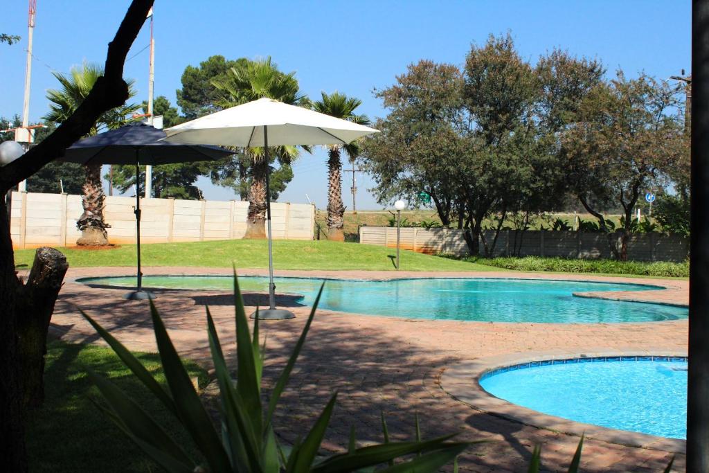 a swimming pool with an umbrella and a swimming pool at Be My Guest Hotel Conference in Sasolburg