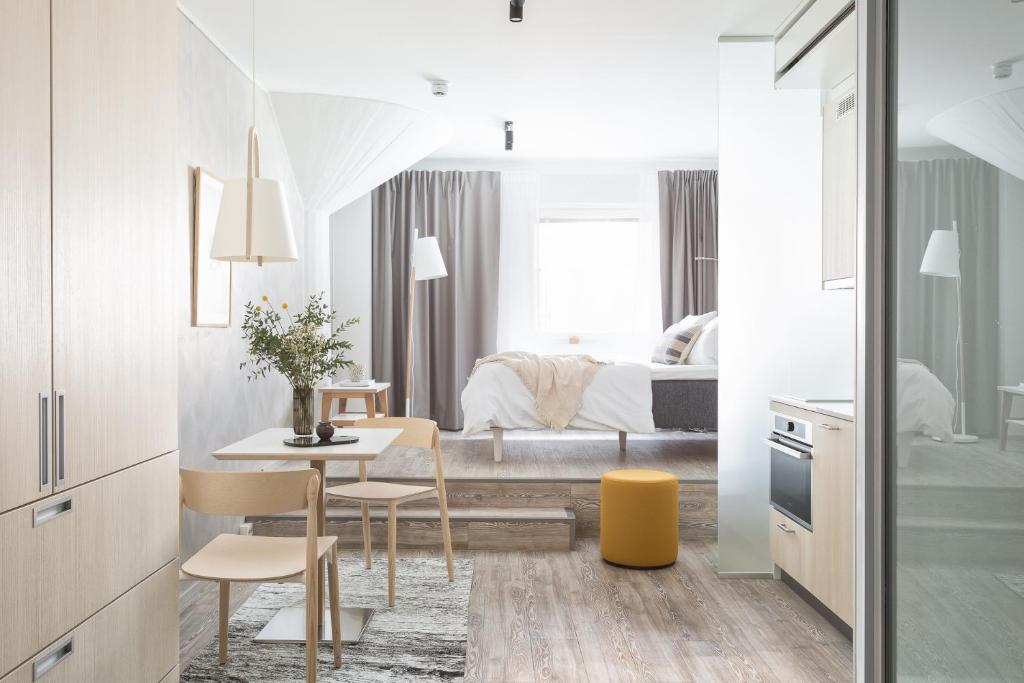 a white bedroom with a bed and a table and chairs at Noli Katajanokka in Helsinki