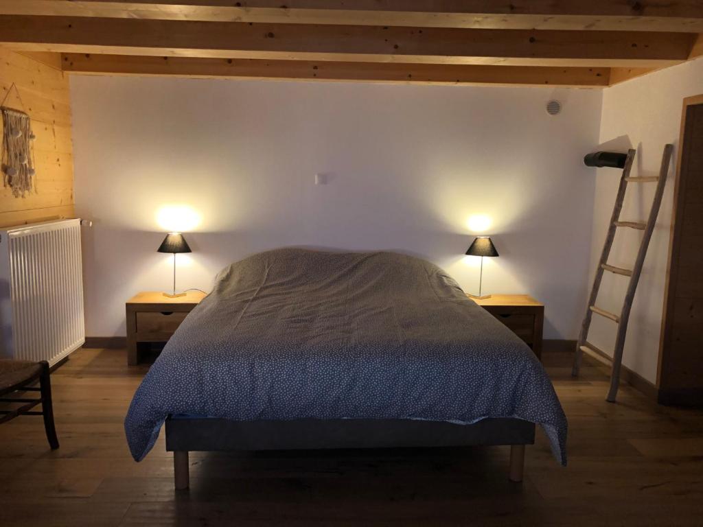 a bedroom with a bed with two lamps and a ladder at Chalet du bois des Fugiers in Ugine