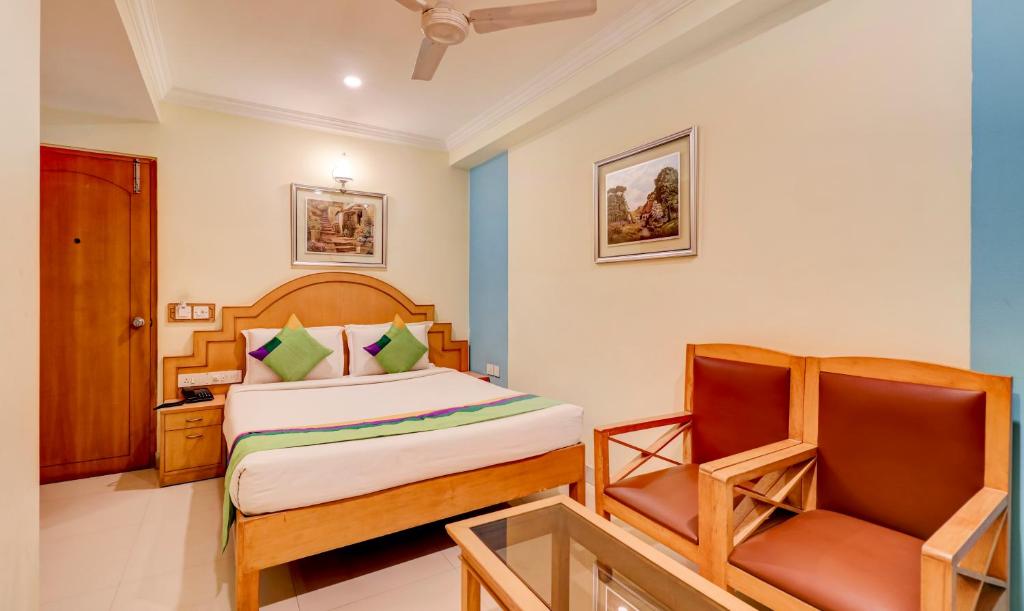 a bedroom with a bed and a chair at Treebo Terminus, Koramangala 5th Block in Bangalore