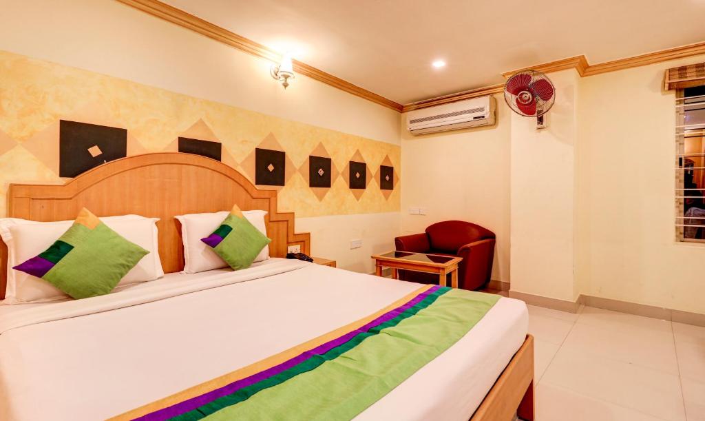 a bedroom with a large bed and a chair at Treebo Terminus, Koramangala 5th Block in Bangalore