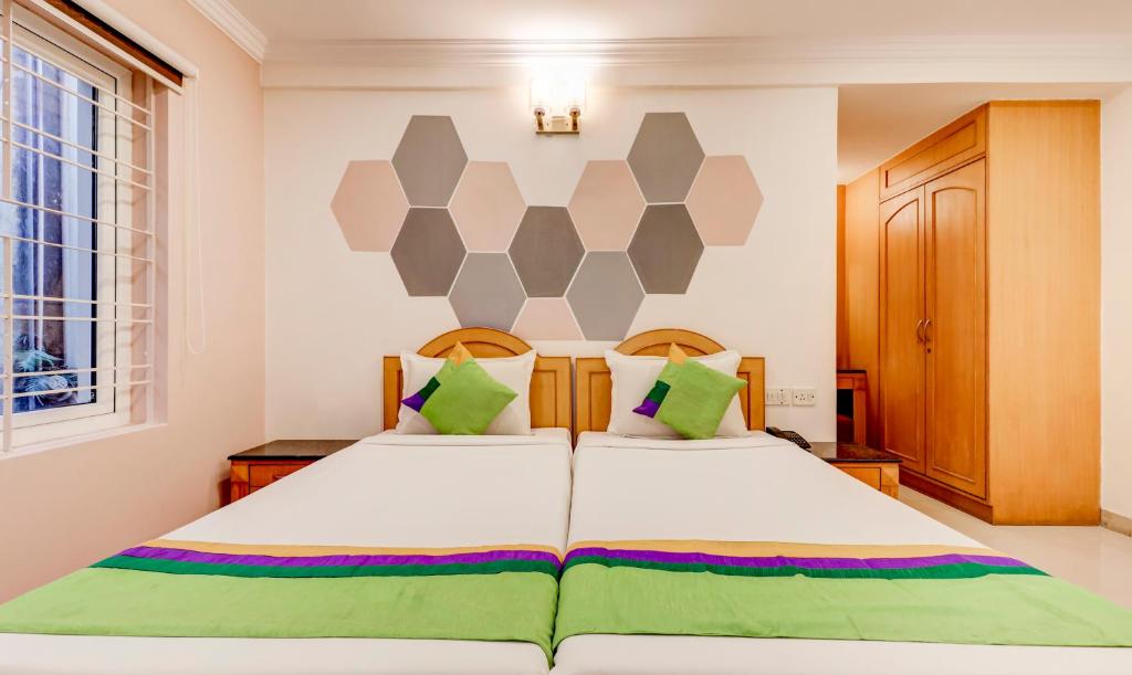 a bedroom with a large white bed with green pillows at Treebo Terminus, Koramangala 5th Block in Bangalore