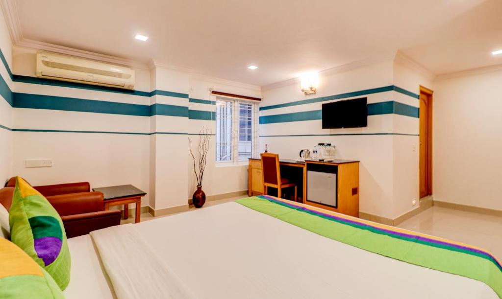 a bedroom with a bed and a desk and a tv at Treebo Terminus, Koramangala 5th Block in Bangalore