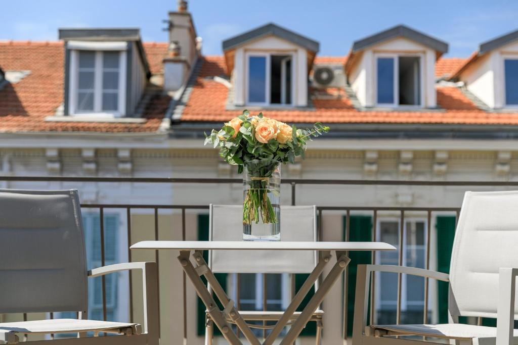 a vase of flowers on a table on a balcony at Hotel Florence Nice in Nice