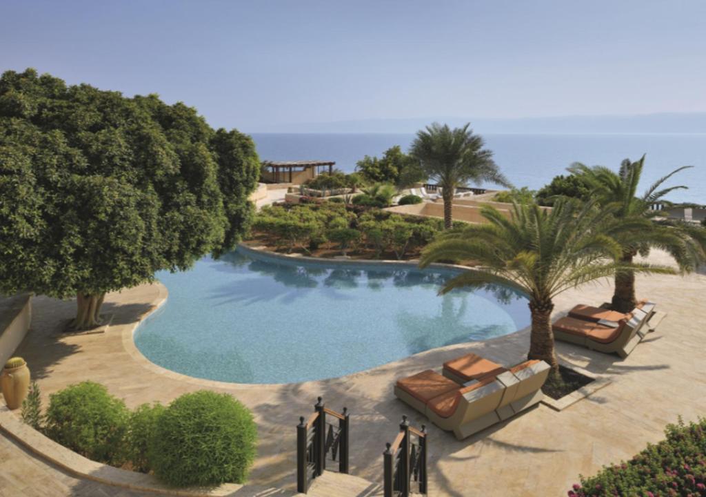 people standing around a pool with a beach at Mövenpick Resort & Spa Dead Sea in Sowayma