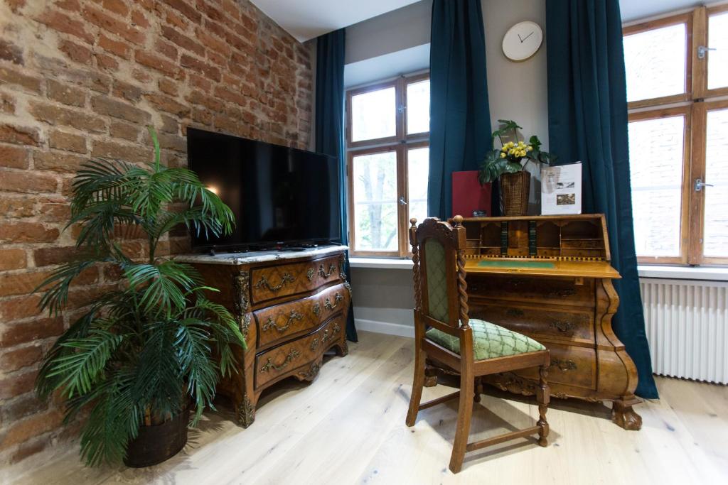 - un salon avec une télévision, un bureau et une plante dans l'établissement Luxury in the Heart of the Old Town, à Cracovie