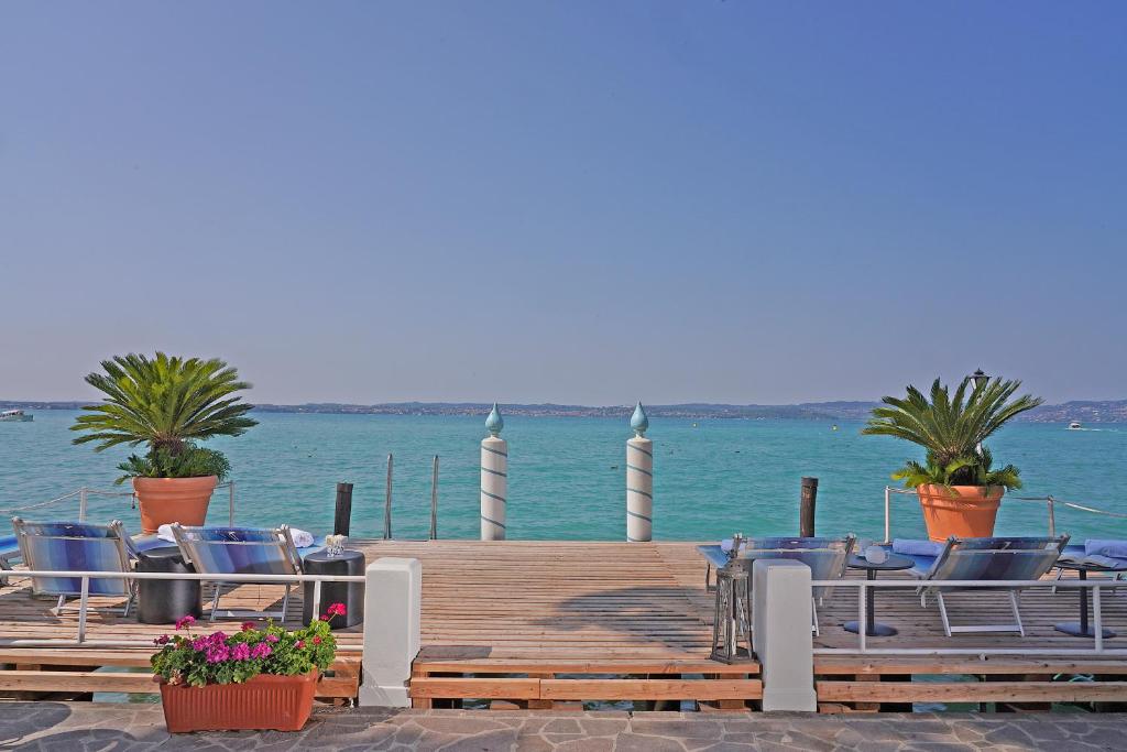 a dock with chairs and plants on the water at Hotel Marconi in Sirmione