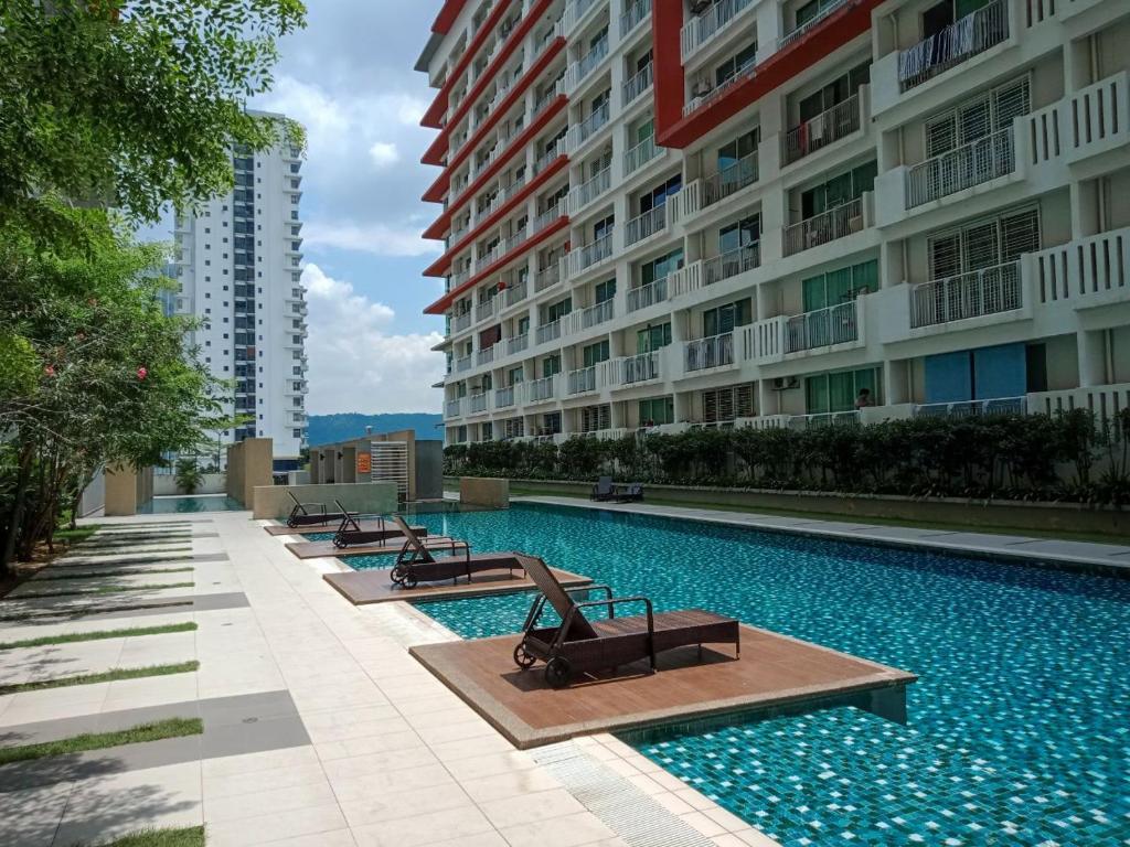 a swimming pool with benches next to a building at Vaincation at Ritze Perdana 2 Damansara Perdana in Petaling Jaya