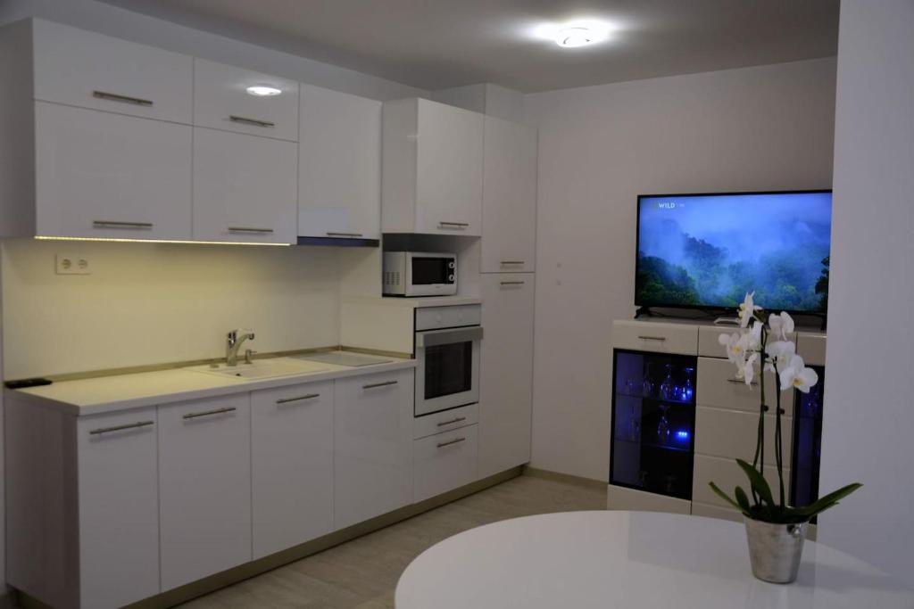 a kitchen with white cabinets and a tv on the wall at Unbeatable Location: New Lux Apartment Varna beach in Varna City