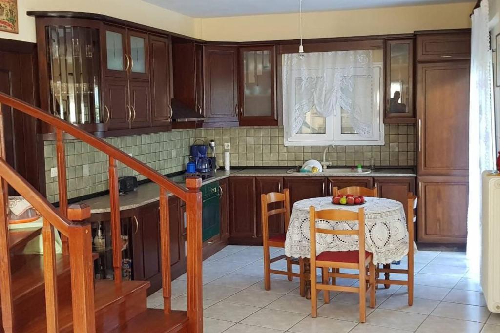 uma cozinha com armários de madeira e uma mesa com cadeiras em Koulas House in Diava em Kalabaka