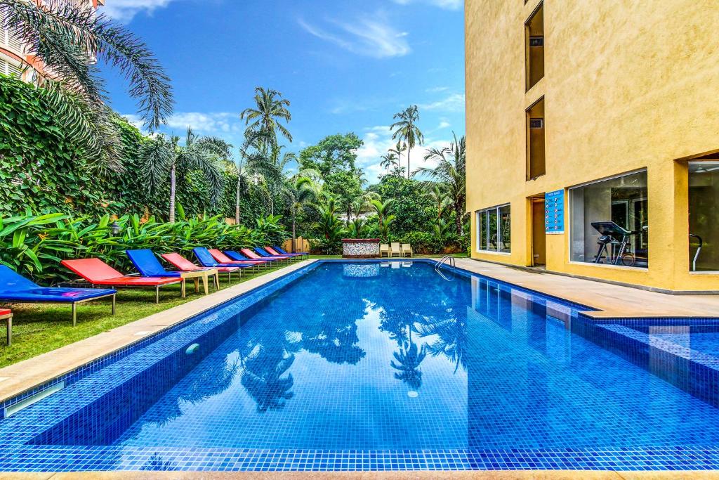 a swimming pool with lounge chairs next to a building at Veera Strand Park Serviced Apartments near Calangute in Calangute