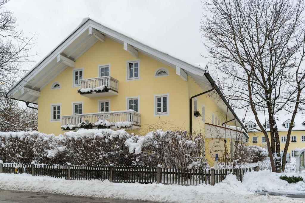 a yellow house with a fence in the snow at Hotel Limmerhof in Taufkirchen