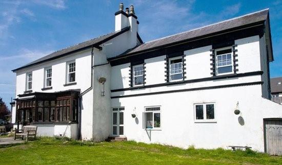 una grande casa bianca con tetto nero di Llanwrtyd Hall B&B Angelis Holistic Retreat a Llanwrtyd Wells
